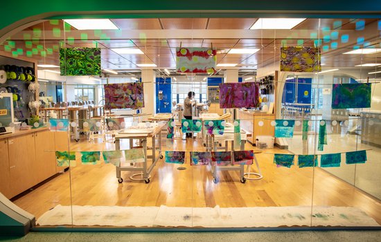 Colorful artwork displayed on a glass window. The Forge workshop can also be seen through the window.