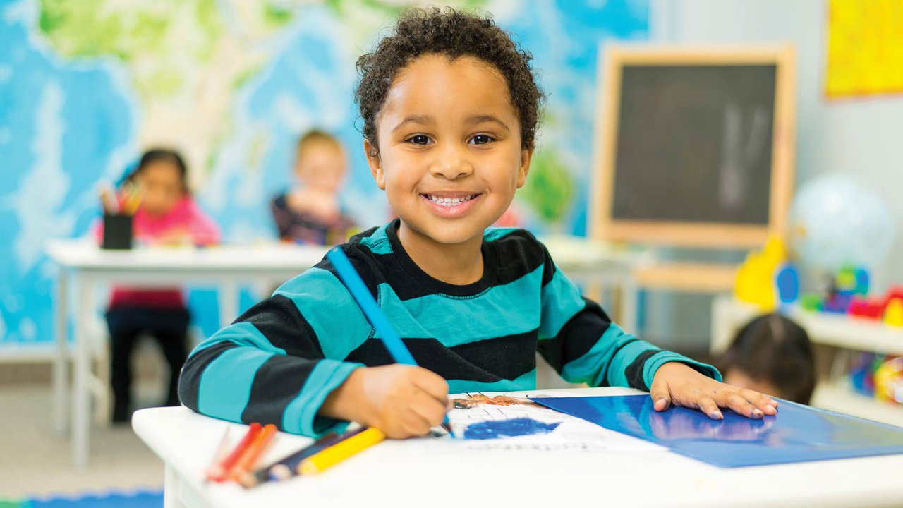 A child smiling in a classroom.